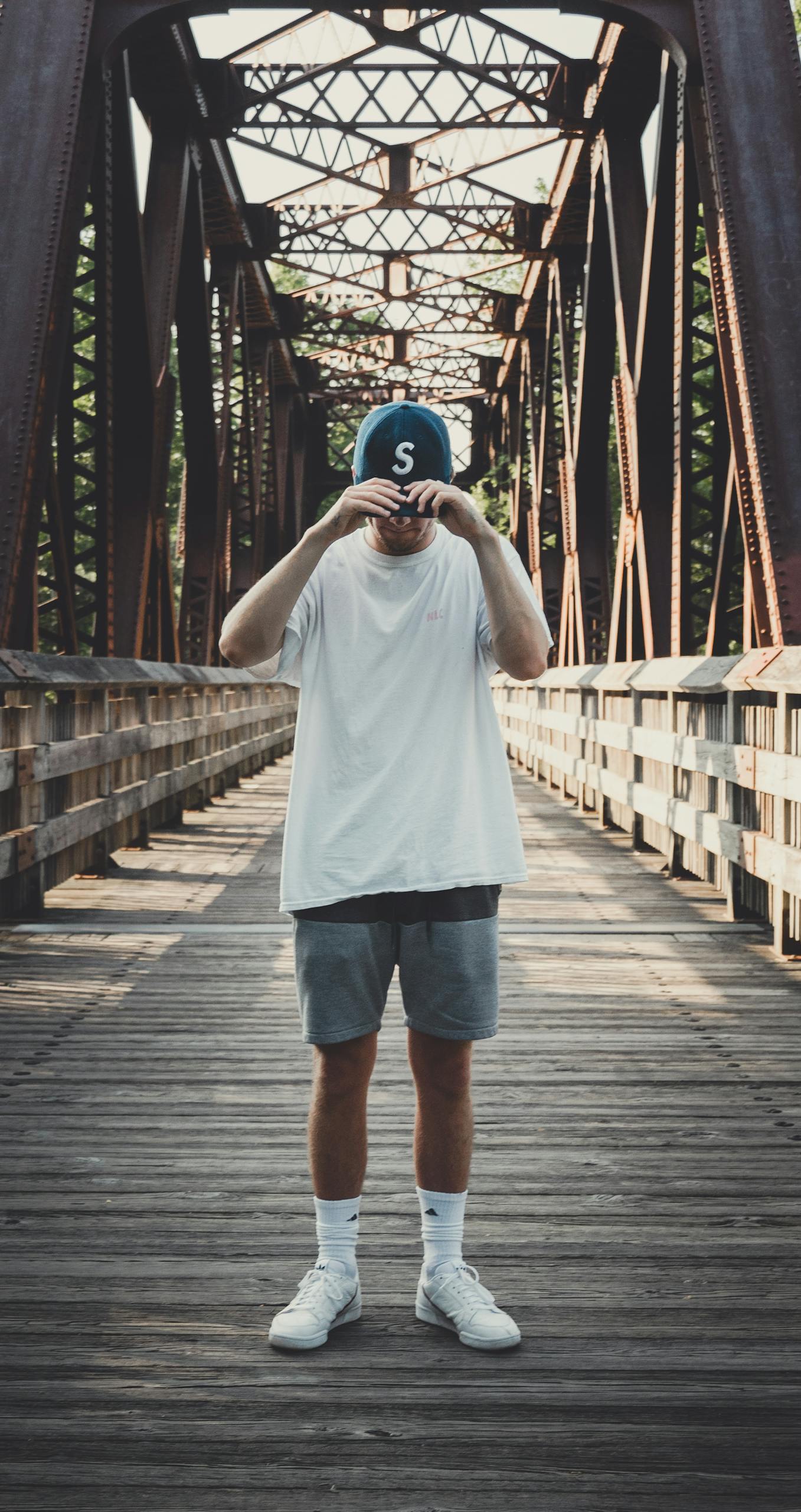 Home Casual fashion photo of a man posing on a metal bridge on a sunny day.