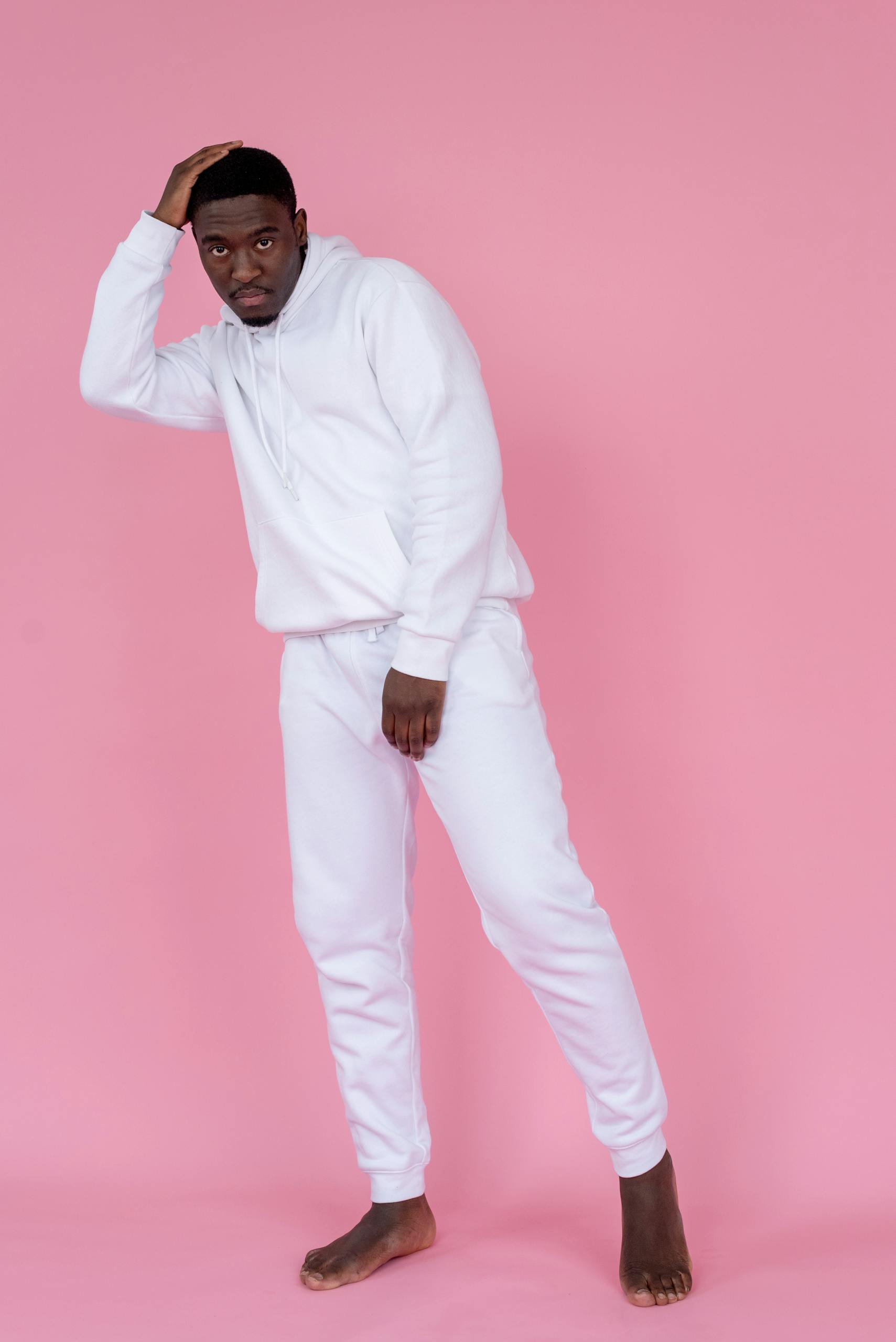 Home Confident young man in white hoodie and joggers posing in studio.
