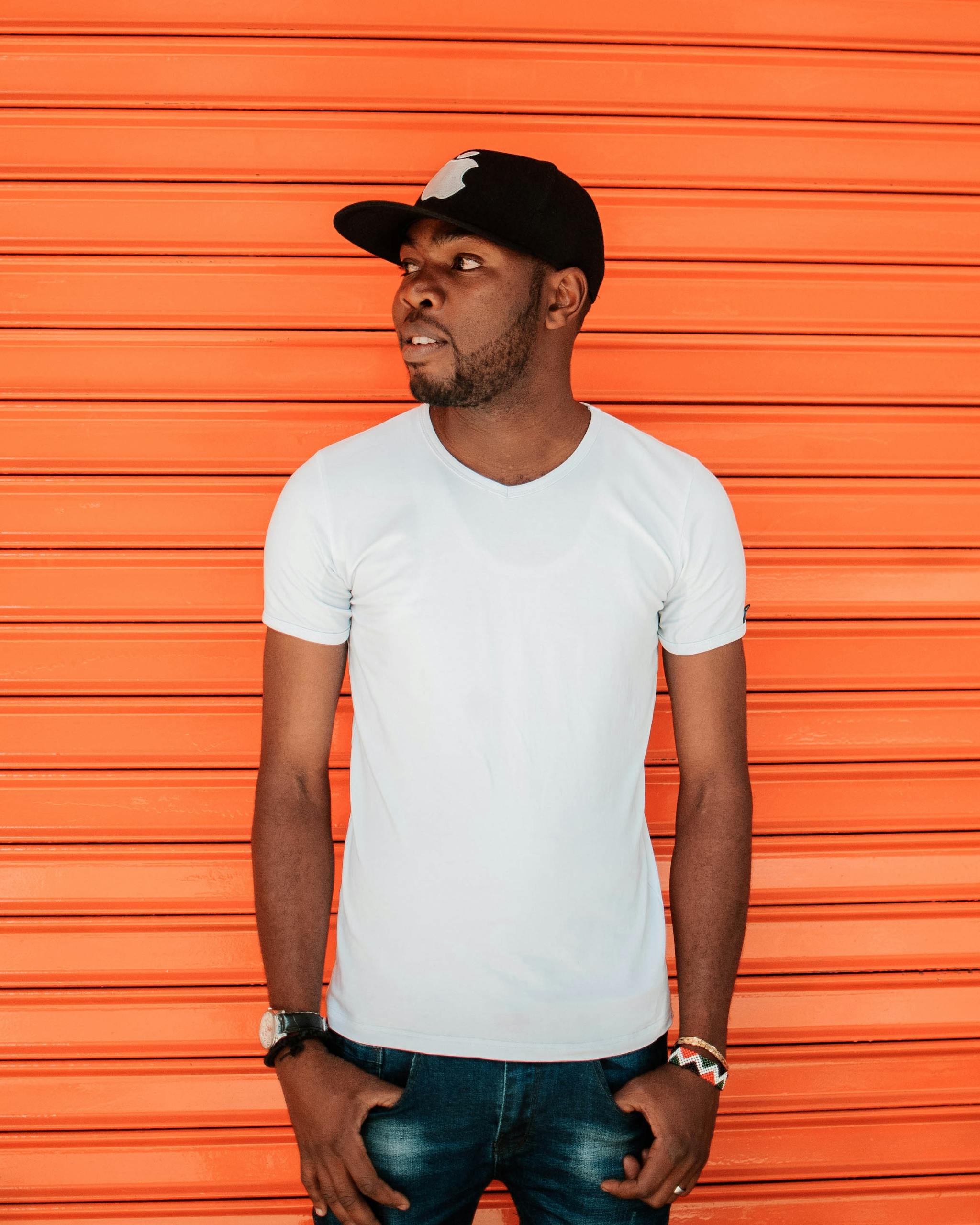 Home Fashionable young man in casual wear poses confidently against a vibrant orange backdrop.